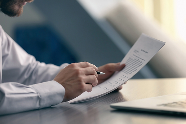 NAIC-Insurance-Services-V2 closeup of business man holding a stack of papers and a pen